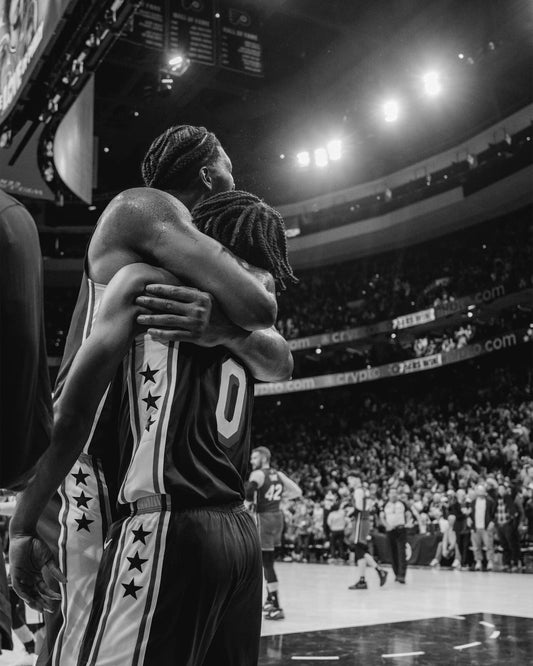 Joel Embiid and Tyrese Maxey hugging black and white canvas wall art